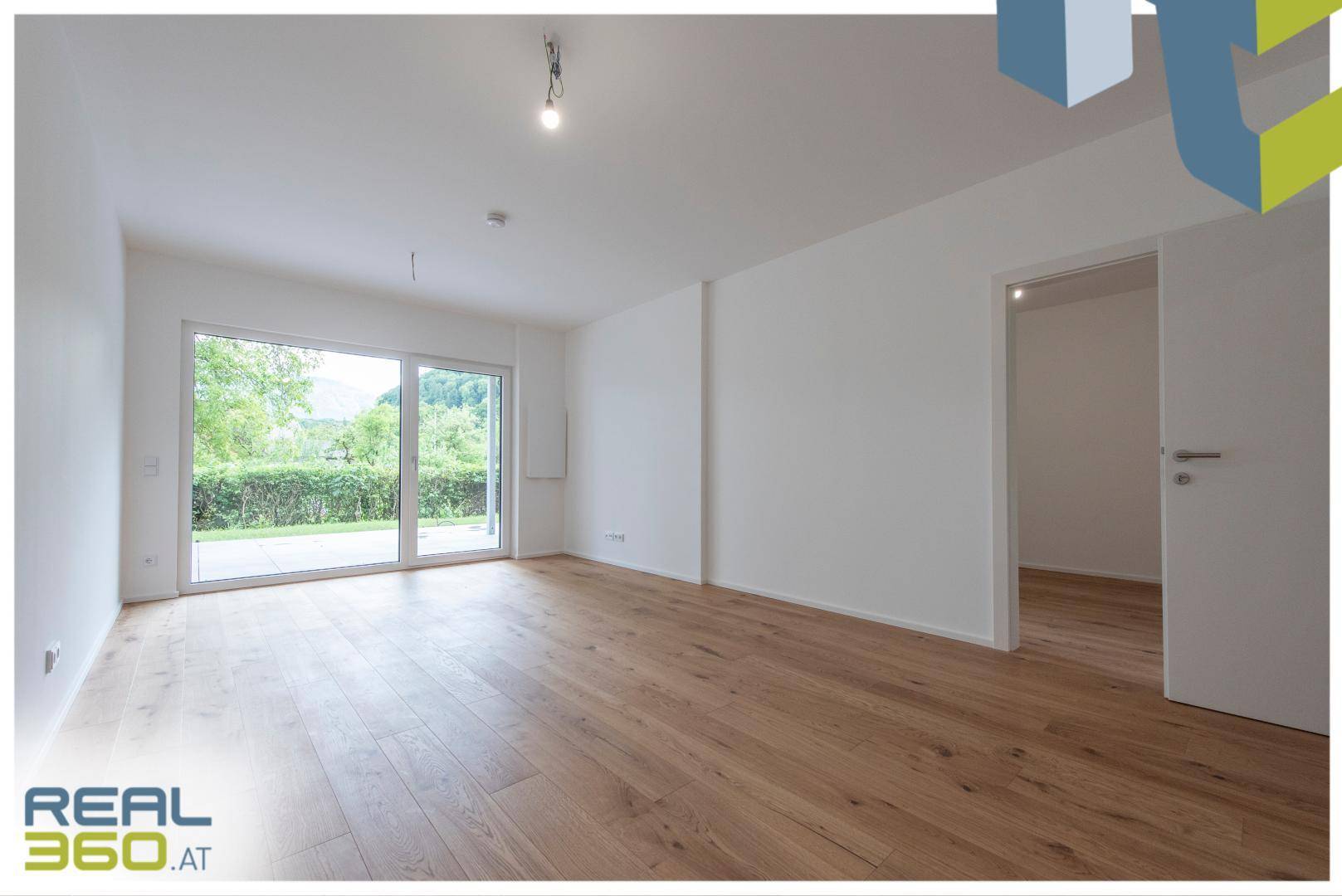 Geräumiges, helles Wohnzimmer mit Holzboden und großer Schiebetür zur Terrasse.