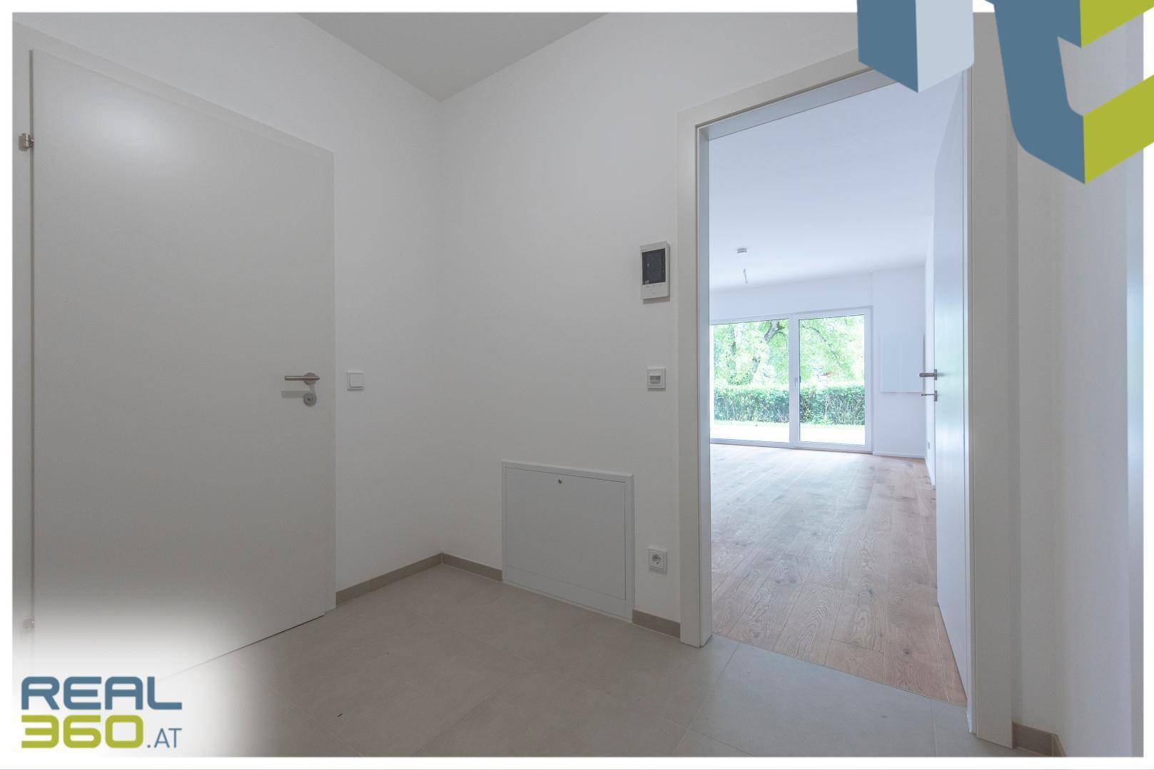 Heller Eingangsbereich einer Wohnung mit weißer Tür und Blick in den Wohnbereich.