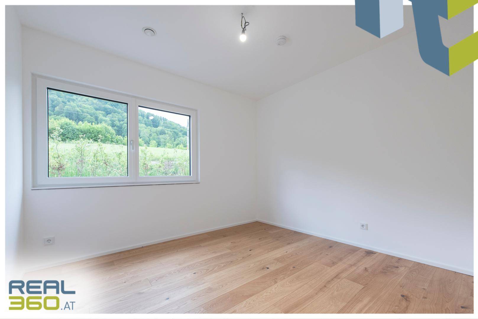 Helles Schlafzimmer mit Holzboden und großem Fenster mit Blick ins Grüne.