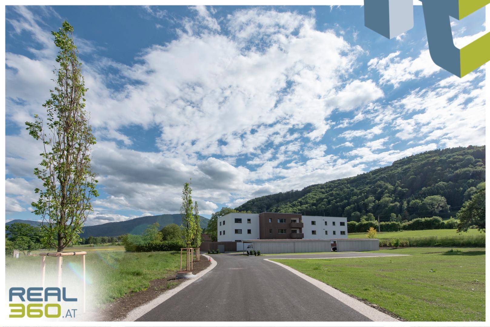 Zufahrt zu einem modernen Wohngebäude in ländlicher Umgebung mit weitem Blick auf die Berge.