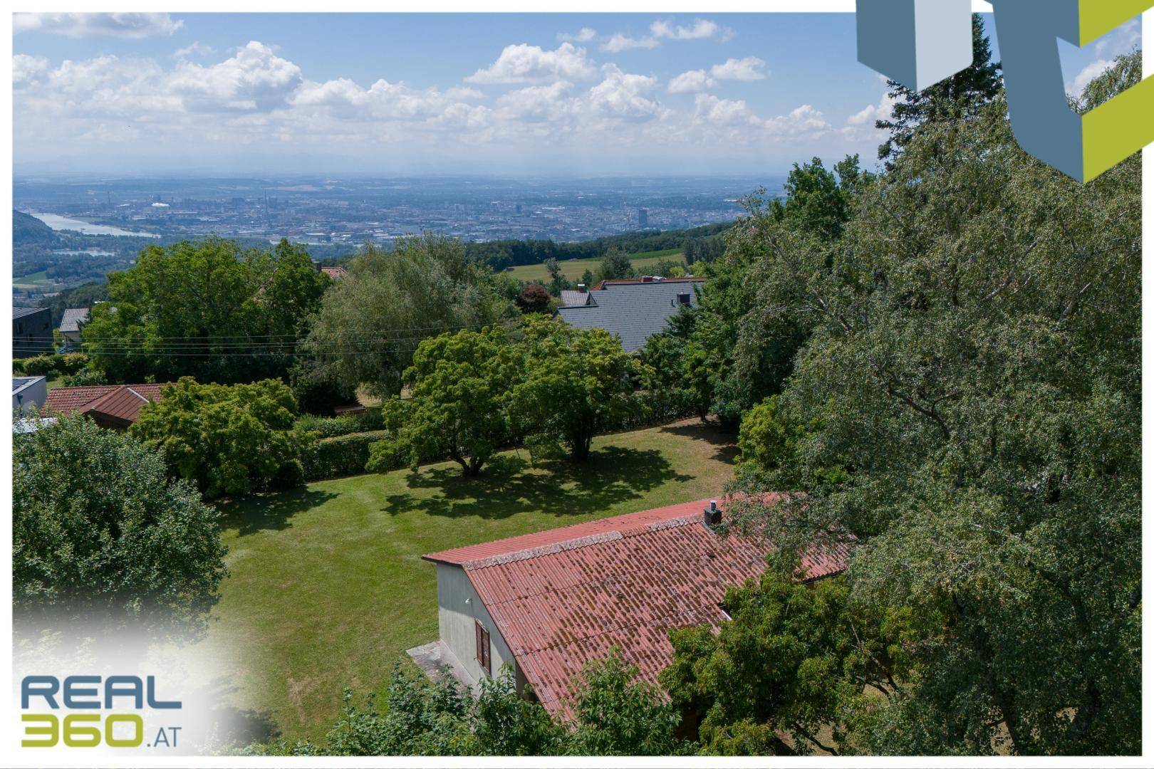 Blick über das Haus und den Garten auf eine weite Stadtlandschaft mit Fluss in der Ferne.