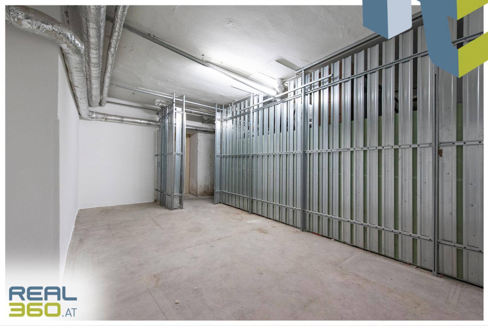 Geräumiger Kellerraum mit Betonboden und Metallabtrennungen für Lagerzwecke.