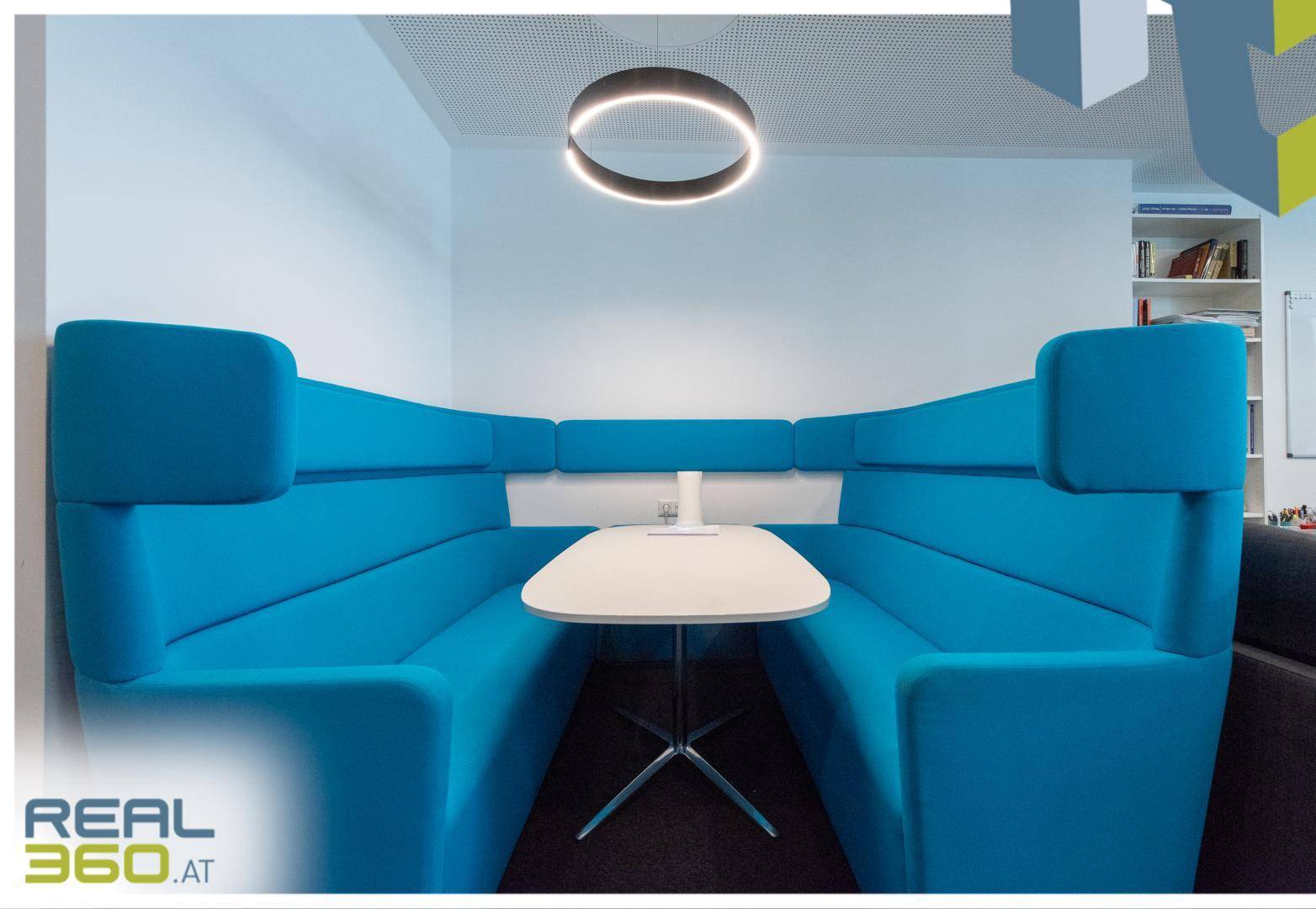 Gemütliche Besprechungsnische mit blauen Polsterbänken und modernem Tisch für informelle Treffen.