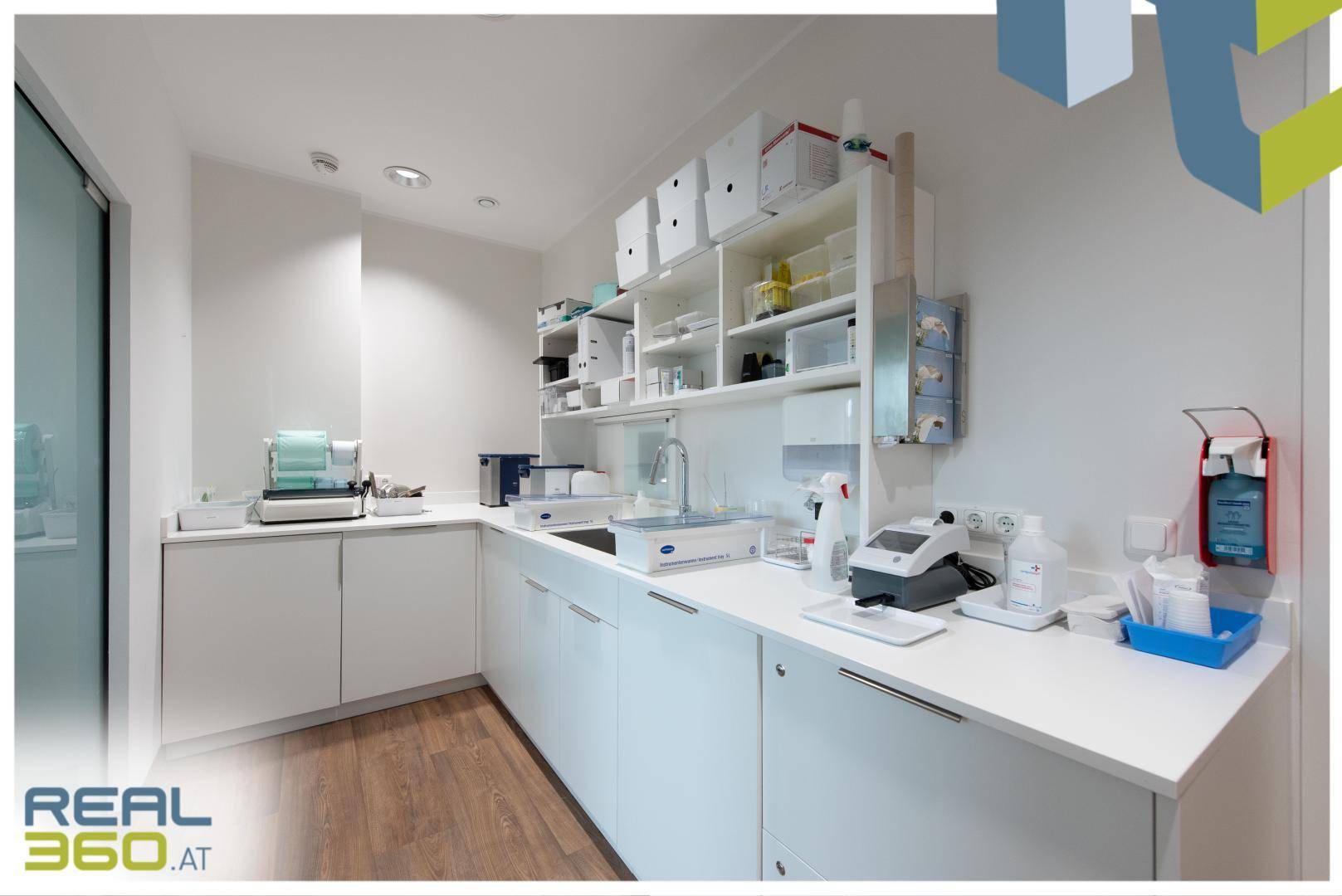 Modernes Labor mit weißen Schränken, Arbeitsflächen und verschiedenen medizinischen Geräten.