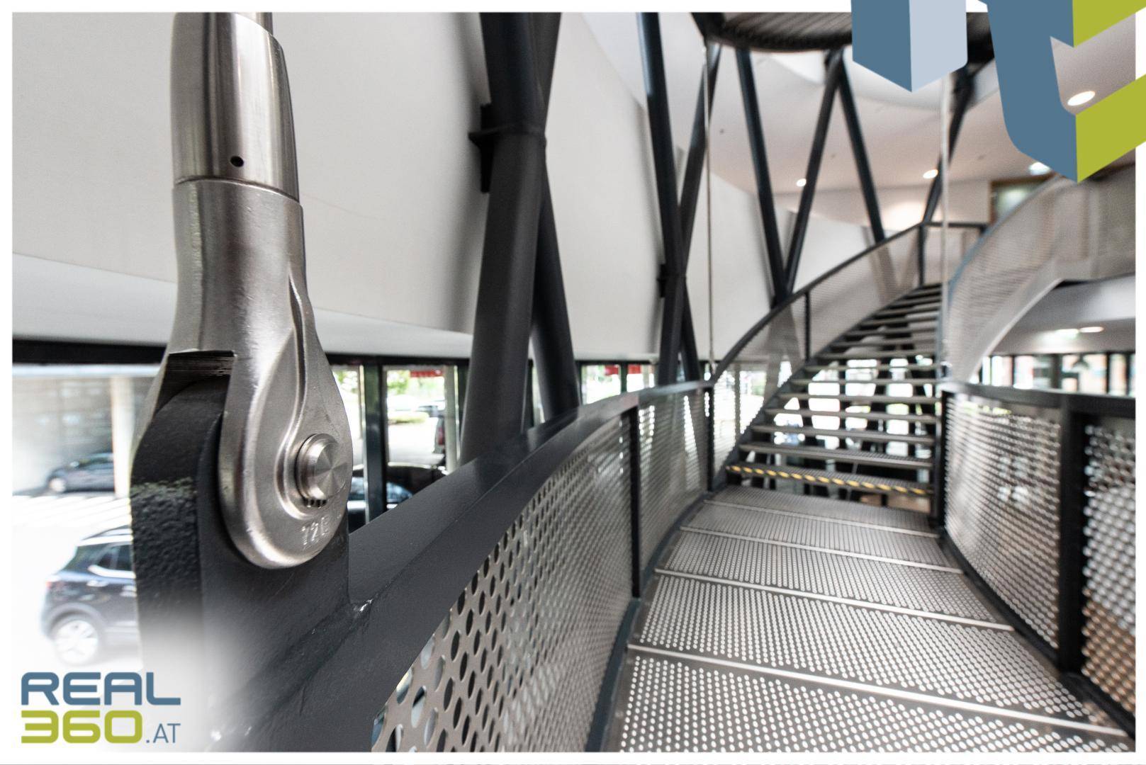 Detailansicht des modernen Treppenhauses mit perforierten Metallgeländern und Blick auf den Außenbereich.