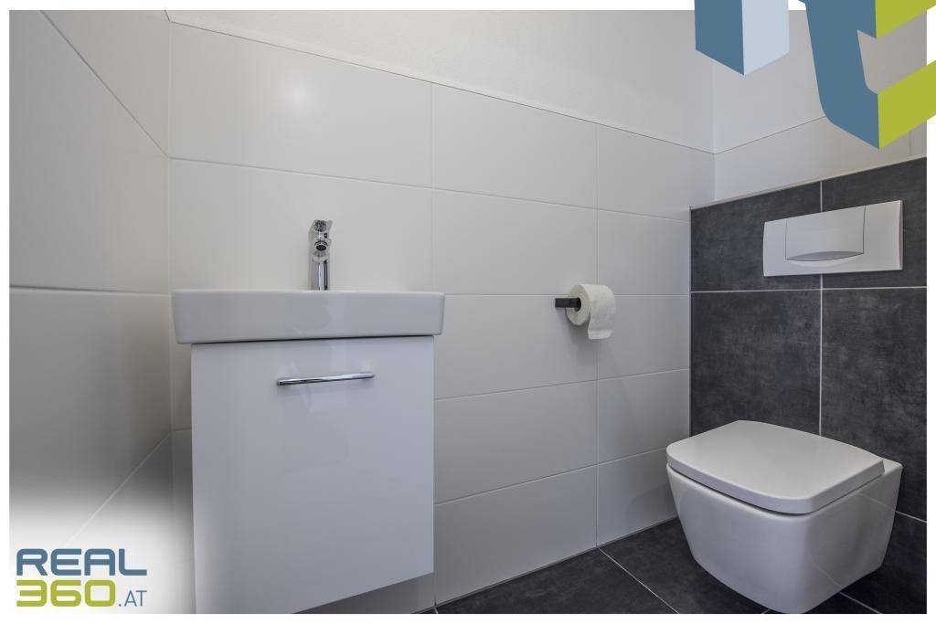 Modernes Gäste-WC mit wandhängendem WC und kleinem Waschbecken.