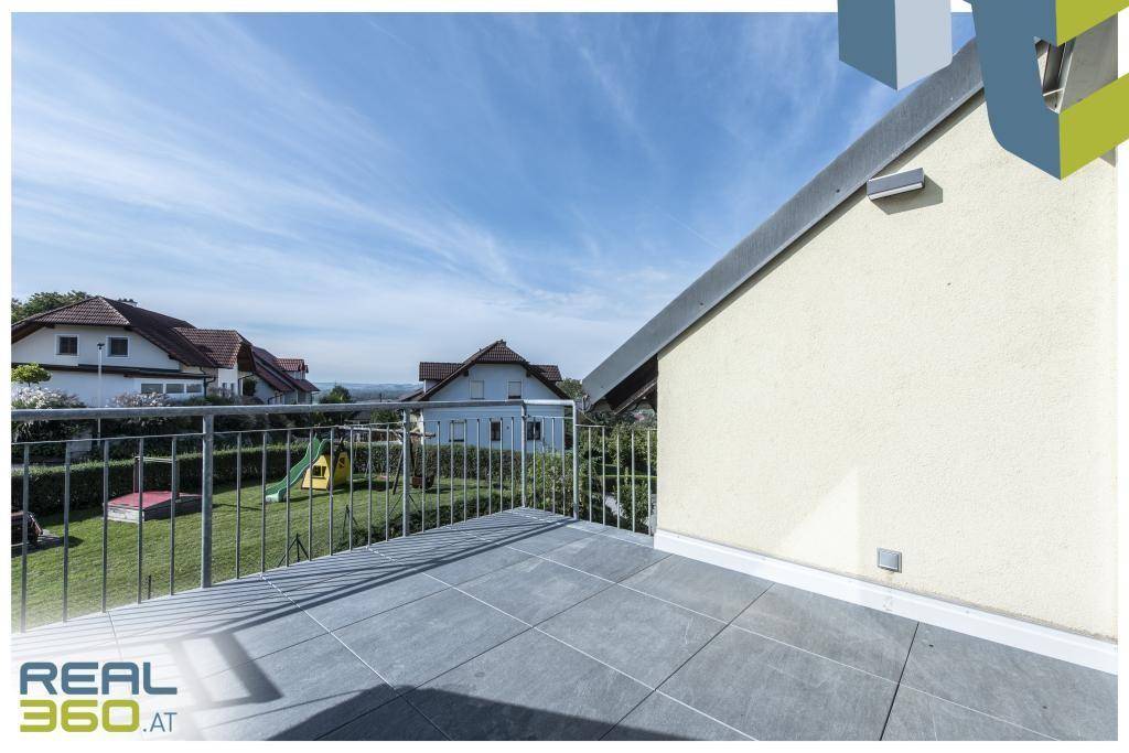 Große geflieste Terrasse mit Metallgeländer und Blick auf die Umgebung.