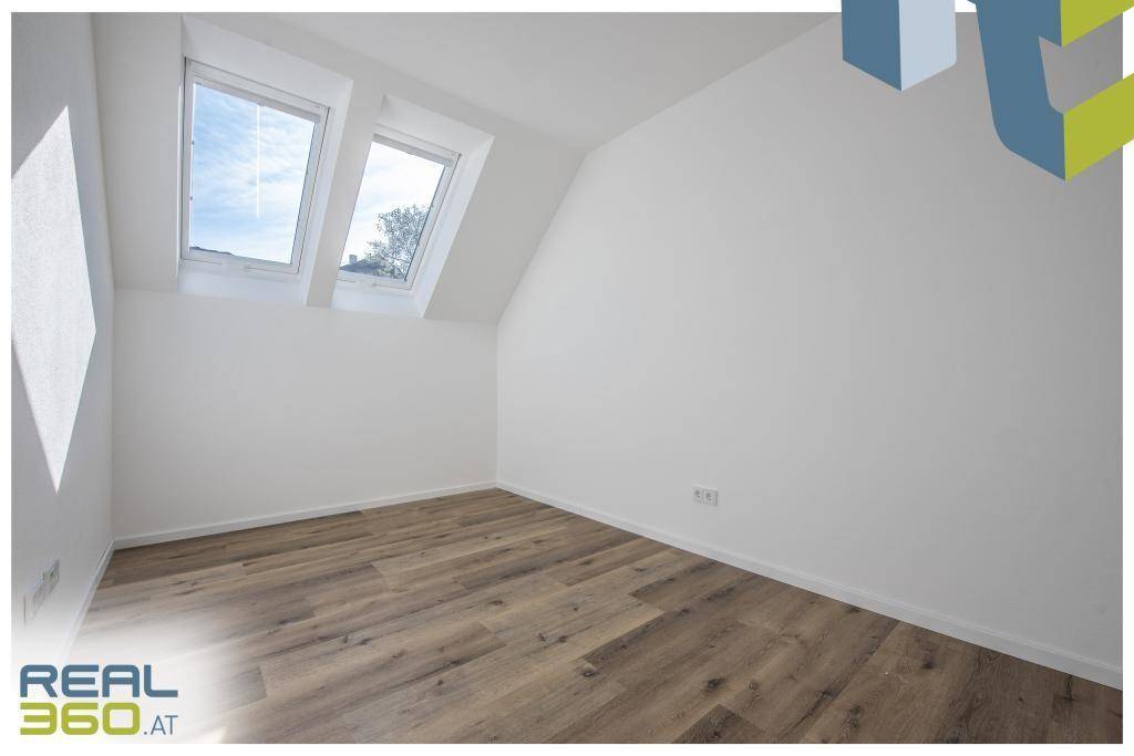 Geräumiges Schlafzimmer mit Dachfenstern und hellem Laminatboden.