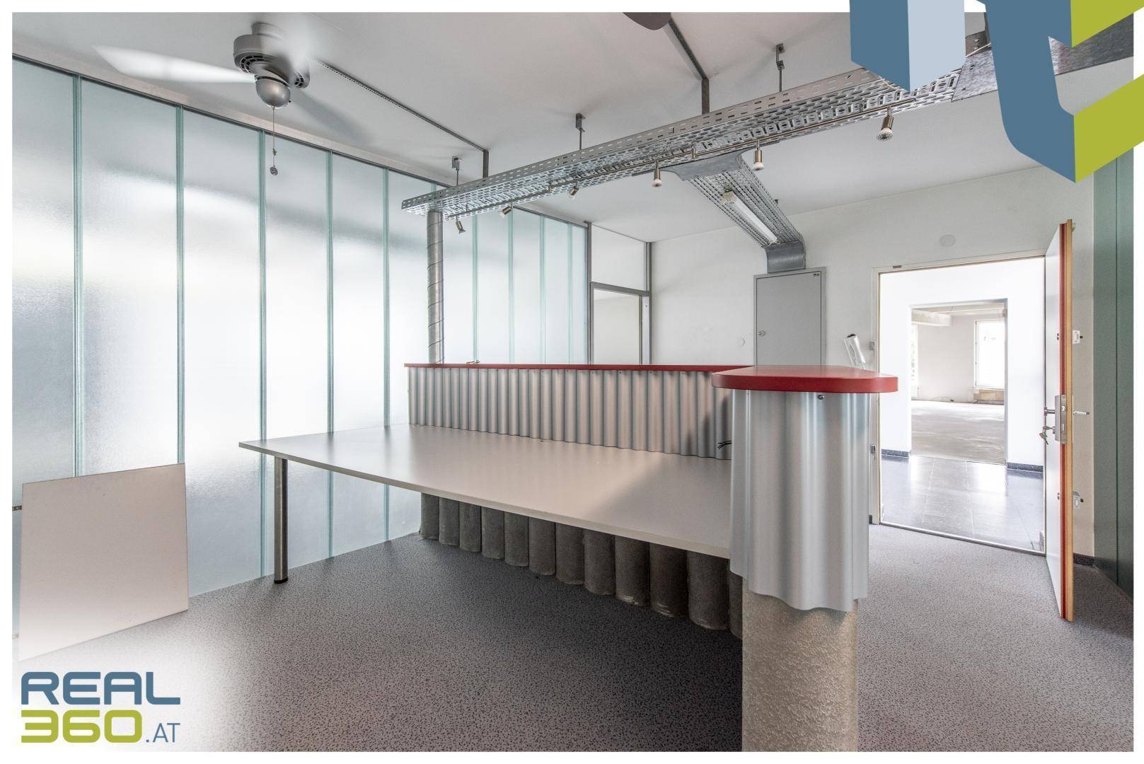 Empfangsbereich eines Büros mit industriellem Design, freiliegenden Kabelkanälen und einer Theke.