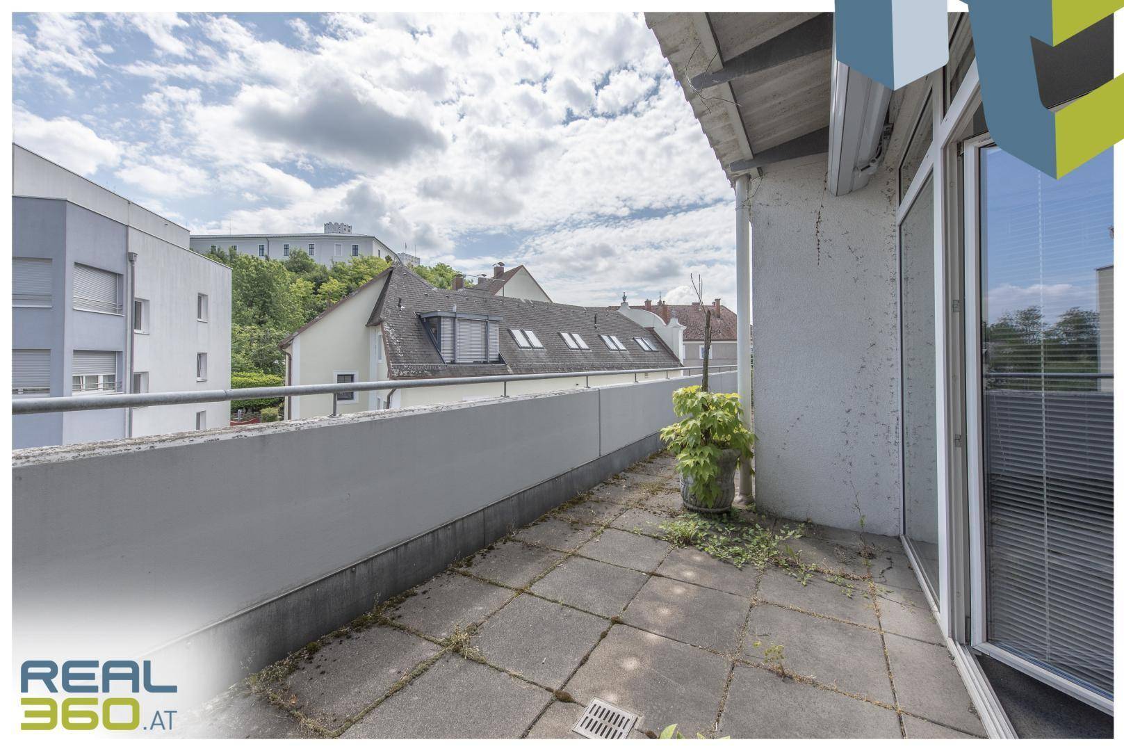 Geräumige Terrasse mit Betonplatten und Blick auf die umliegenden Dächer und Gebäude.