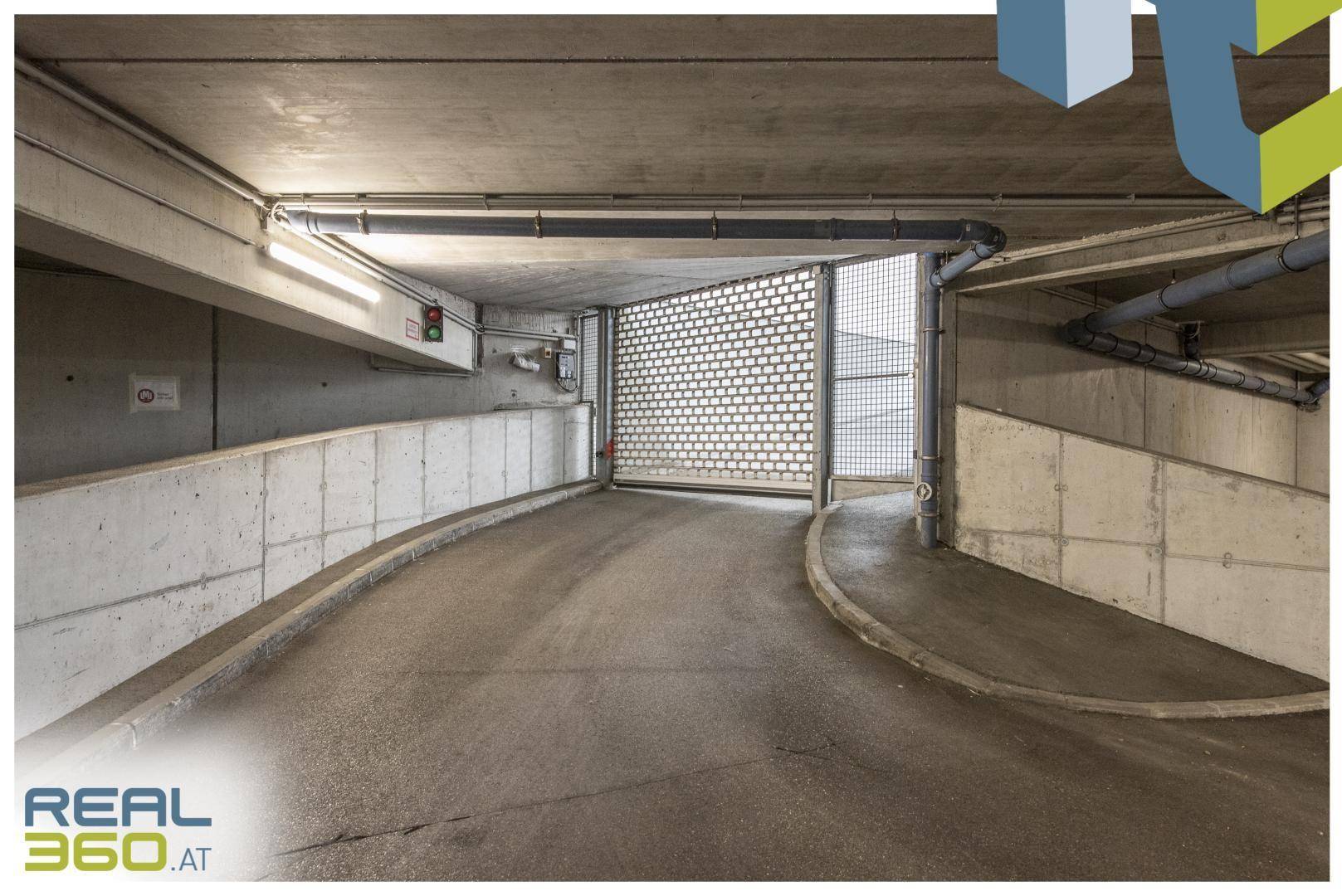 Zufahrt zur Tiefgarage mit Rampe und Metallgittertor.