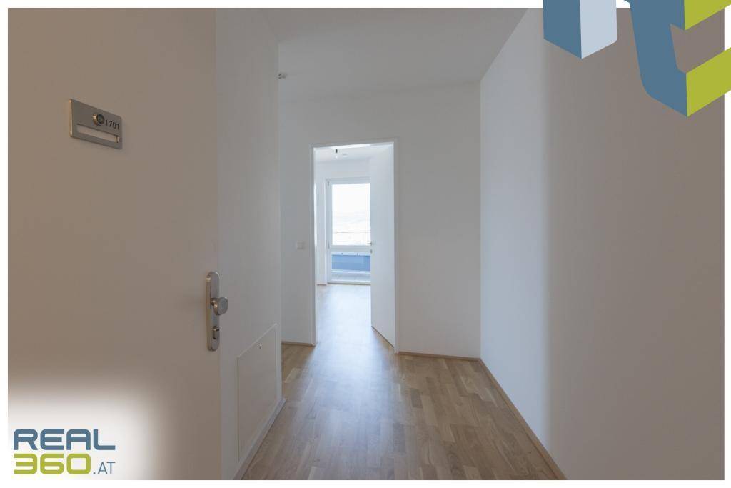 Heller Flur mit Parkettboden und weißen Wänden, der zu einem weiteren Zimmer führt.