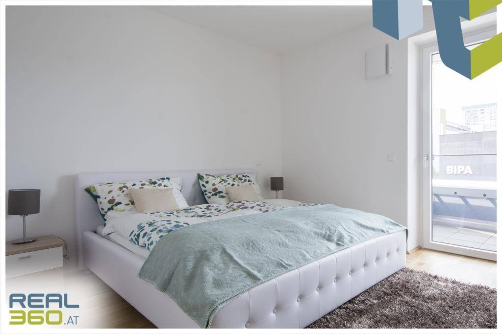Gemütliches Schlafzimmer mit weißem Bett, Nachttischen und direktem Zugang zum Balkon.