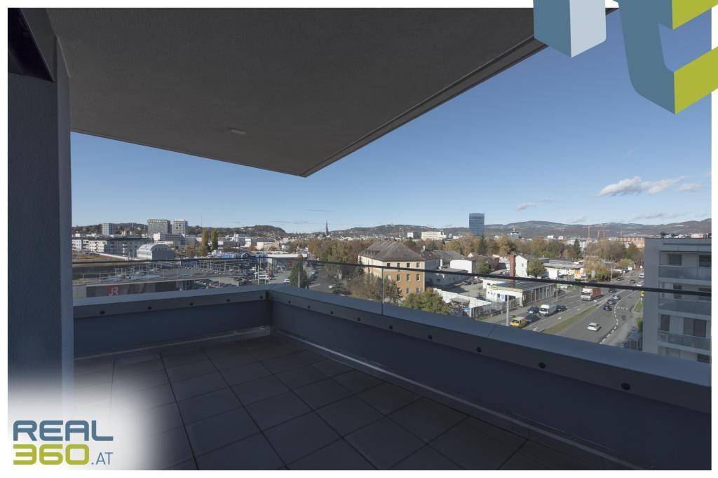 Weitläufige Terrasse mit Fliesenboden und Glasgeländer, mit Panoramablick über die Stadt.