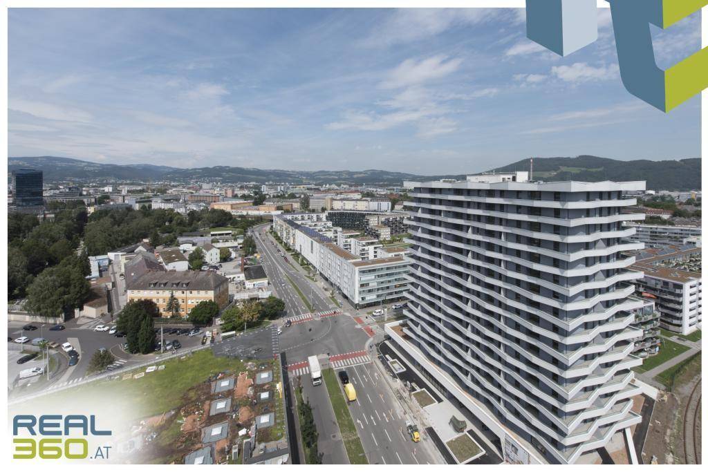 Luftaufnahme des modernen Gebäudes und der umliegenden Stadtlandschaft mit Straßen und Häusern.