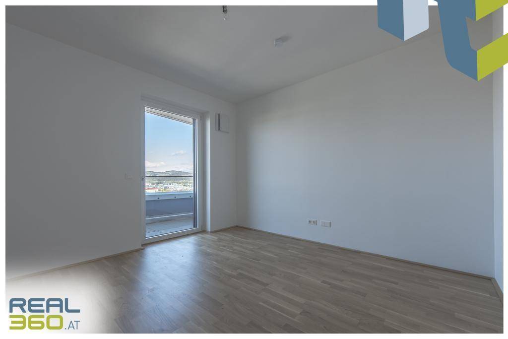 Geräumiges, helles Zimmer mit Parkettboden und Zugang zu einem Außenbereich.