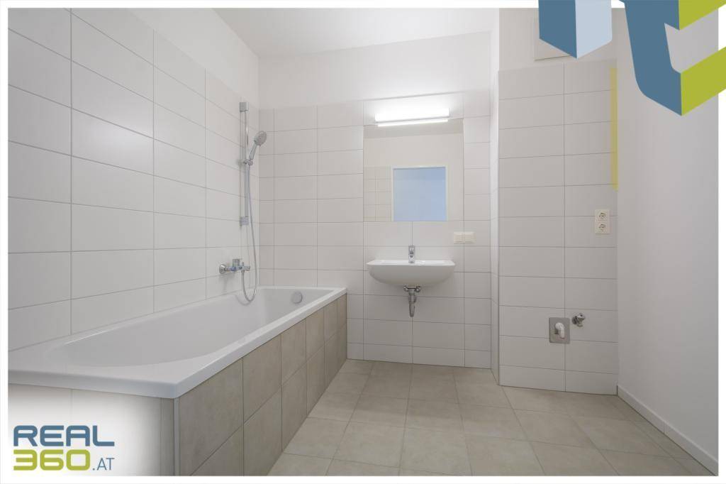 Modernes Badezimmer mit weißen Fliesen, Badewanne mit Duschfunktion und Einzelwaschbecken.