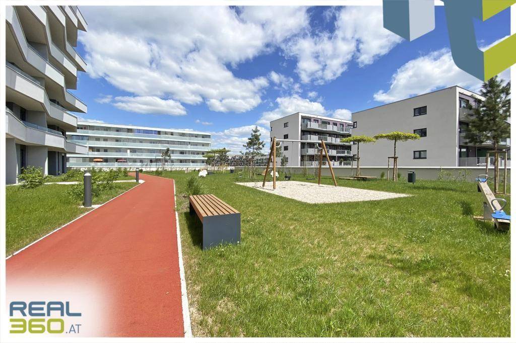 Gemeinschaftlicher Gartenbereich mit Spielplatz, Schaukeln, Rasenfläche und Spazierweg.