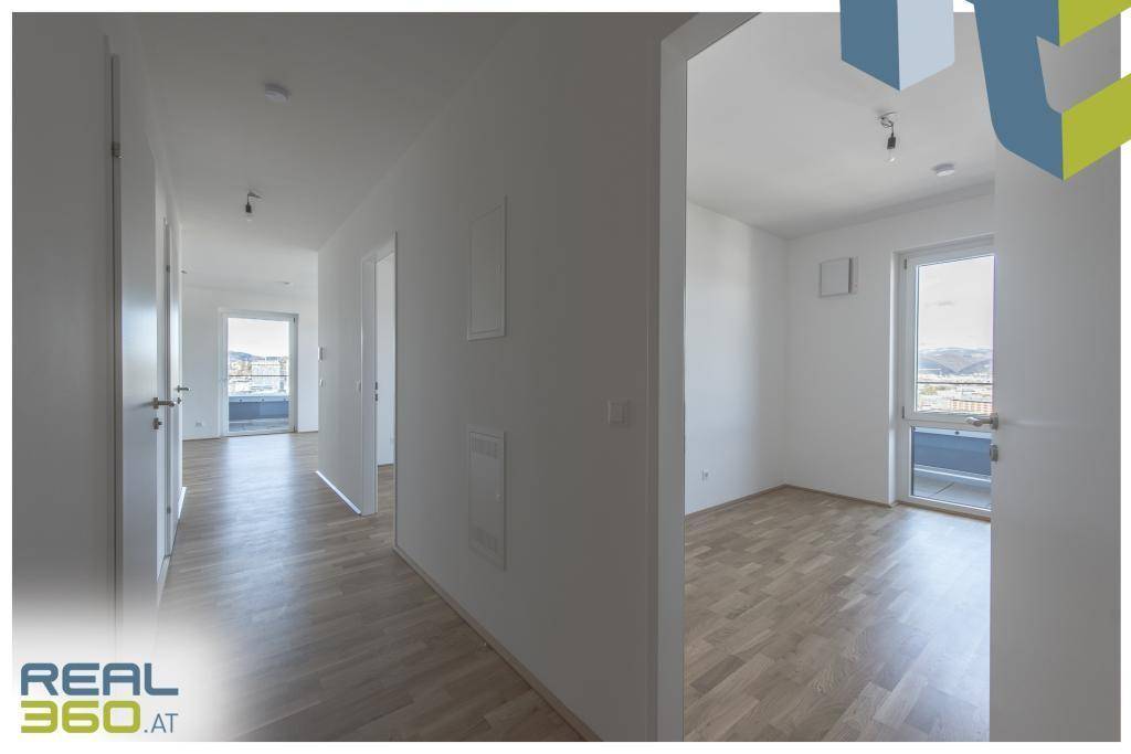 Geräumiger Flur mit mehreren Türen und Blick in ein helles Zimmer mit Fenster.