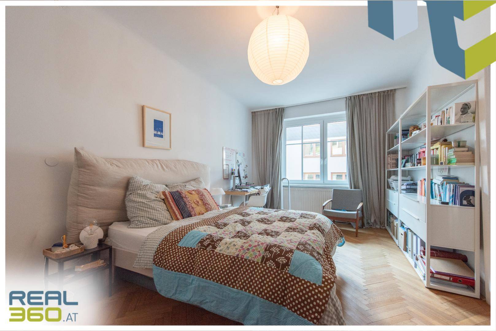 Helles Schlafzimmer mit großem Bett, Bücherregal und klassischem Fischgrätparkettboden.