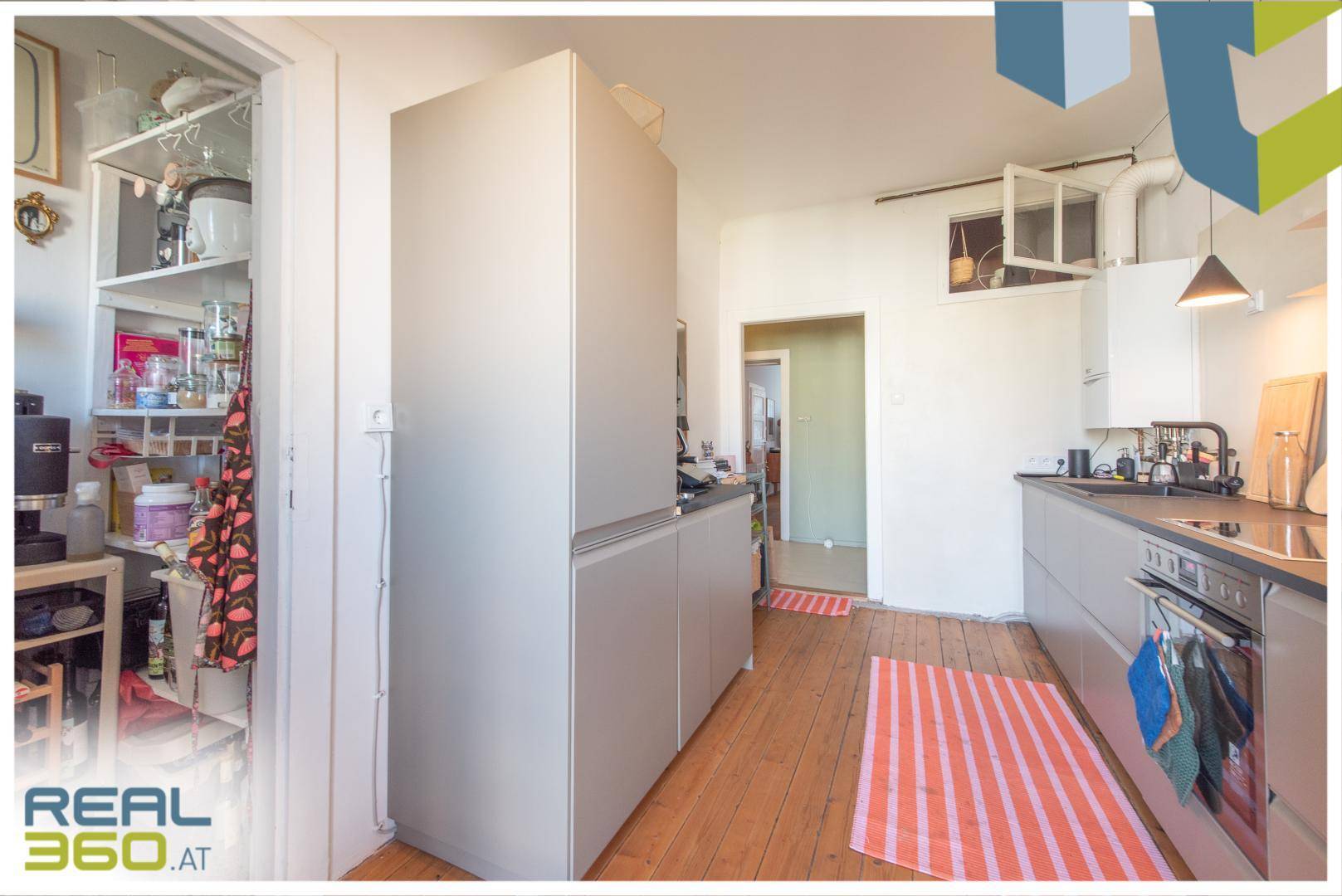 Helle Küche mit integrierten Geräten, offenem Regal und Holzdielenboden.