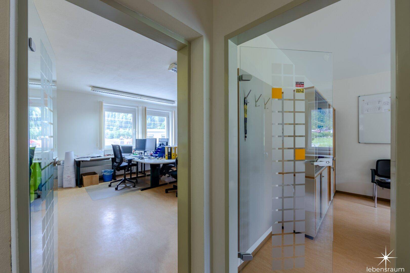 Zwei helle Büroräume, getrennt durch eine Glastür, mit Blick auf die Umgebung.