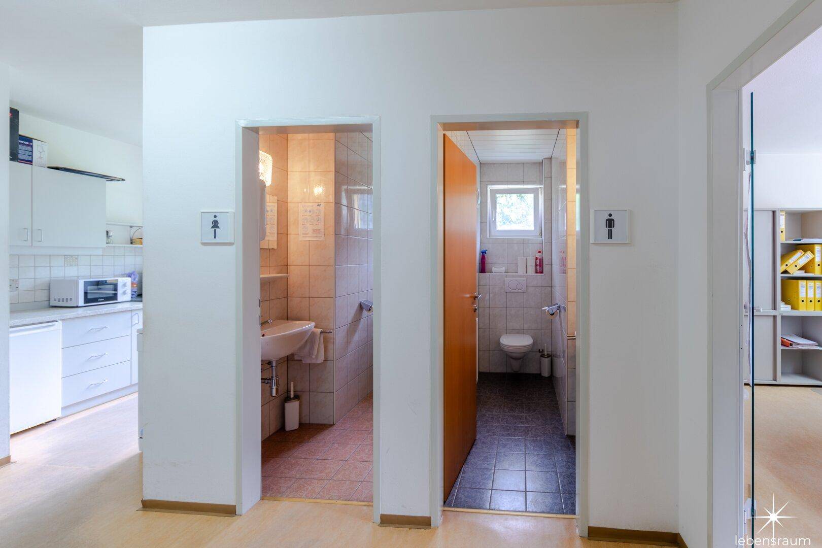 Flur mit Zugang zu zwei getrennten Toilettenräumen, die mit Fliesen ausgestattet sind.