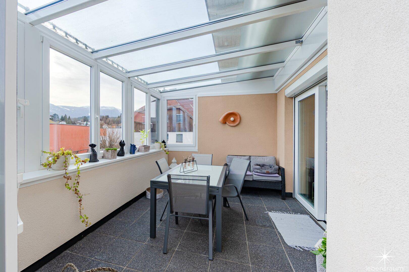 Heller Wintergarten mit Glasdach und Essbereich, bietet weite Ausblicke auf die Umgebung.