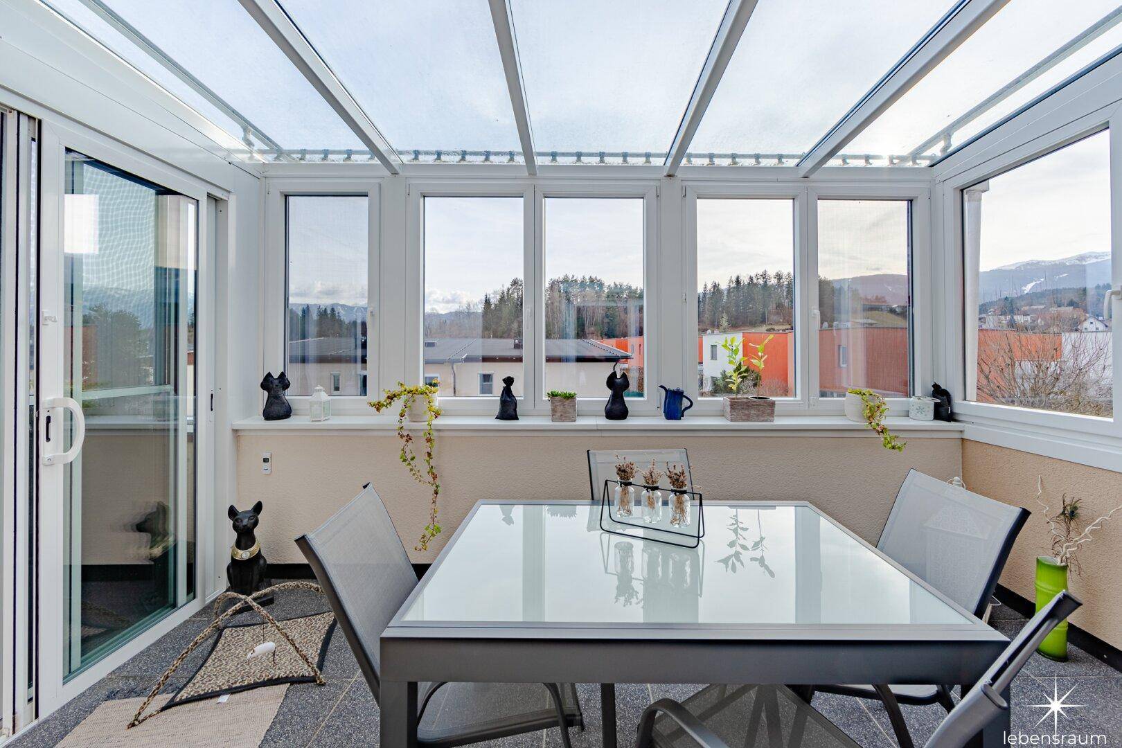 Heller Wintergarten mit großflächigen Fenstern und Glasdach, ideal für Mahlzeiten mit Aussicht.