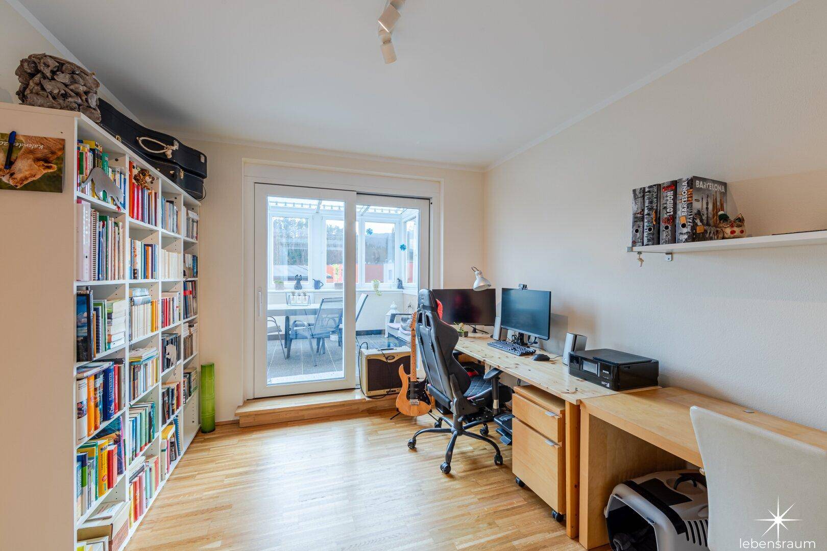 Helles Arbeitszimmer mit Parkettboden und direktem Zugang zur verglasten Terrasse.