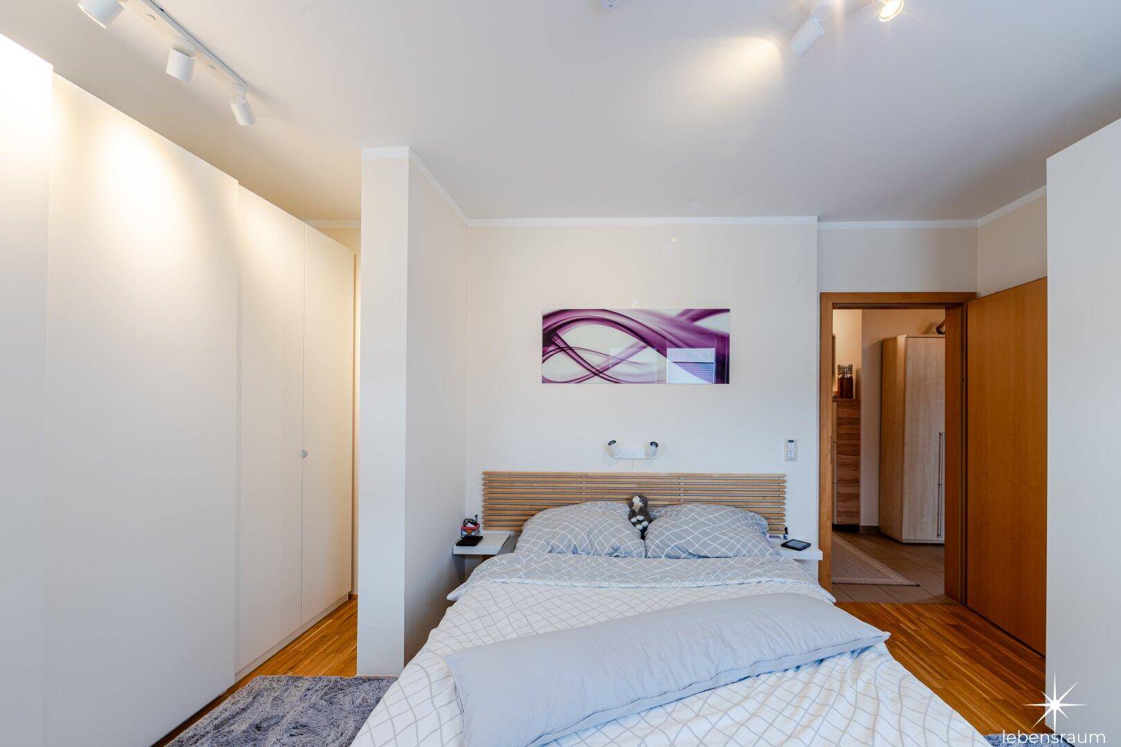 Schlafzimmer mit Parkettboden und integrierten Schränken, hell und funktional eingerichtet.