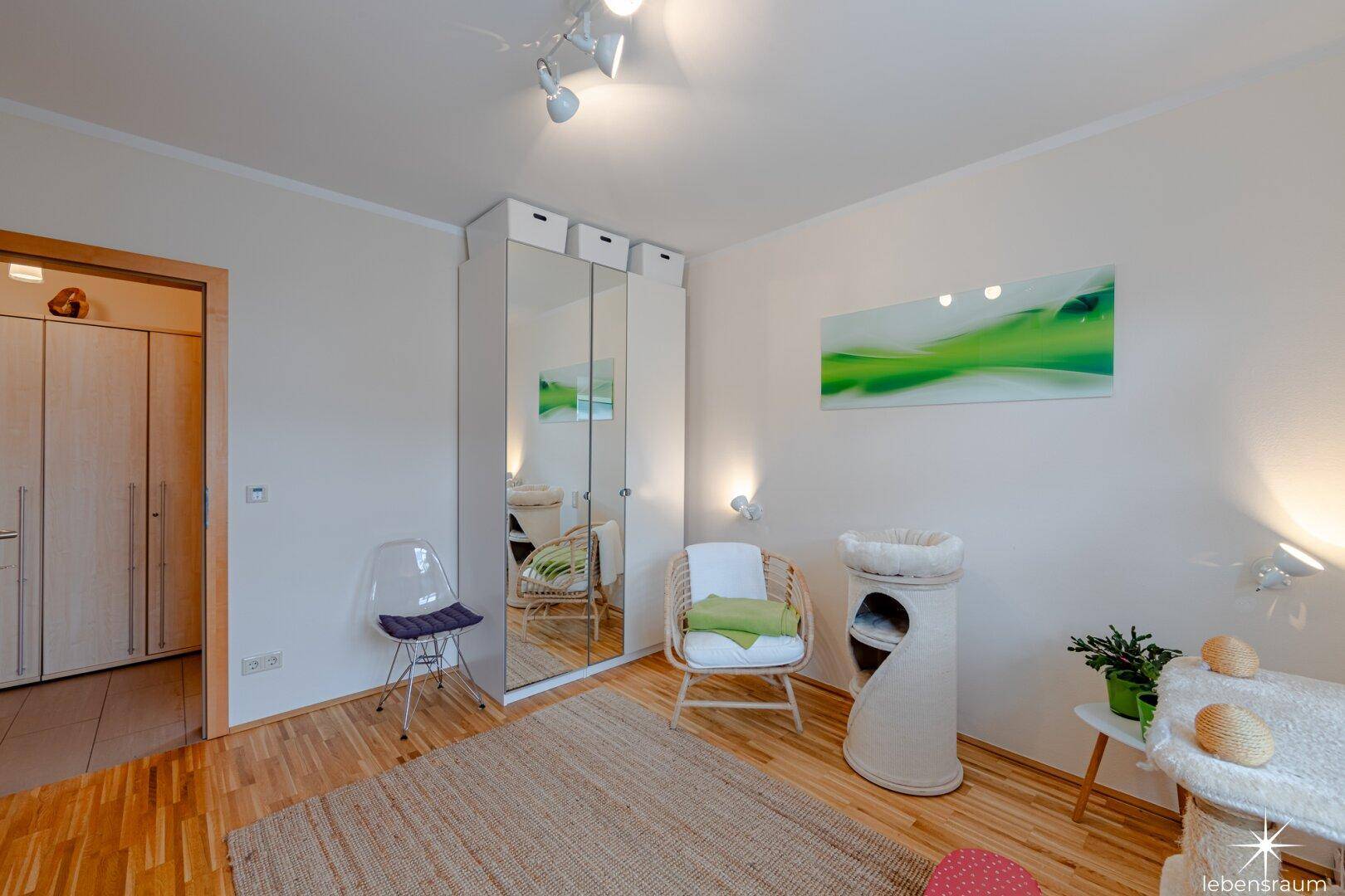 Schlafzimmer mit Parkettboden und Spiegelschrank, hell und einladend eingerichtet.
