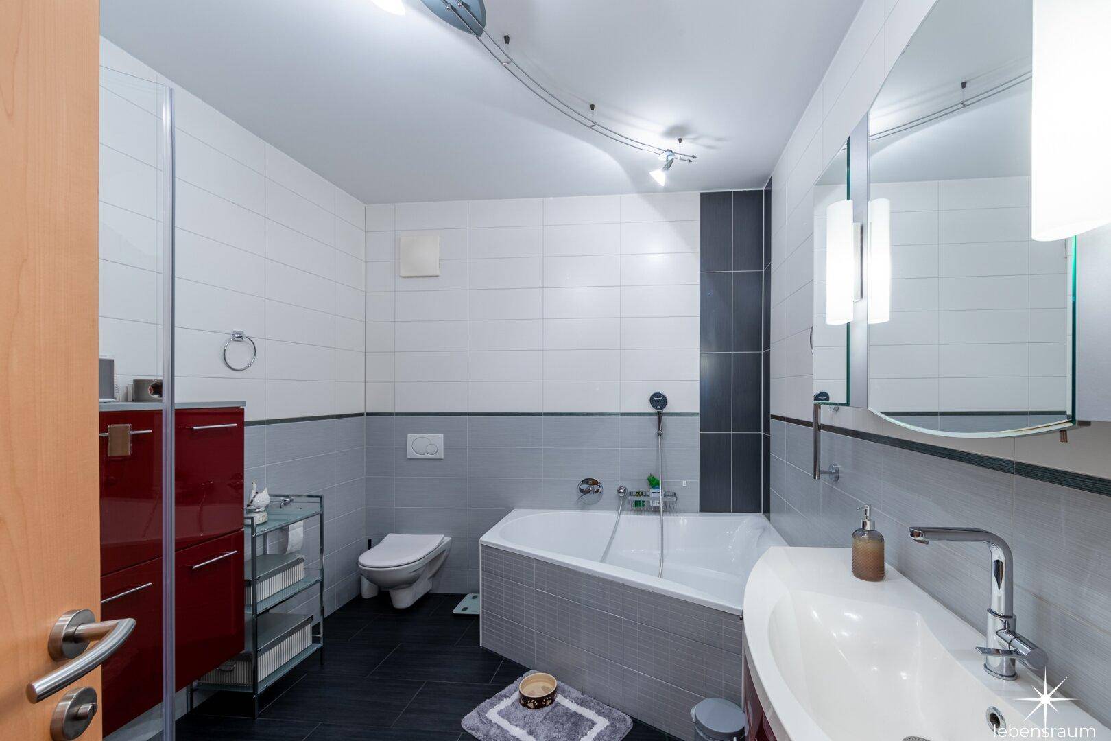 Modernes Badezimmer mit Badewanne, Dusche und dunklen Fliesen, funktional und stilvoll.