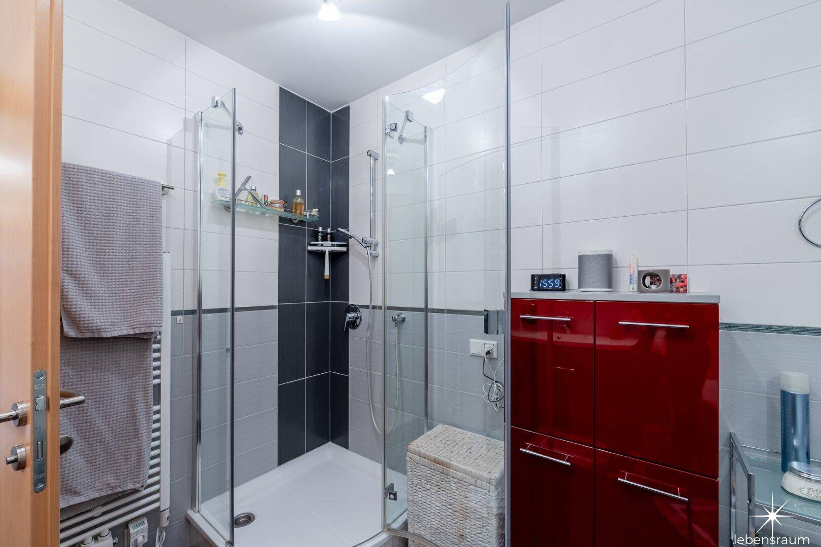 Badezimmer mit Duschkabine und dunklen Bodenfliesen, praktisch und pflegeleicht.