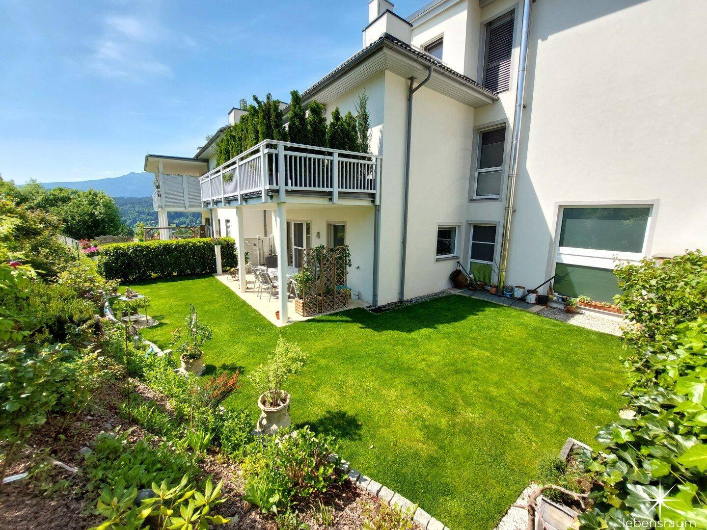 Ansicht des Gebäudes von der Gartenseite mit Terrasse und gepflegter Rasenfläche.