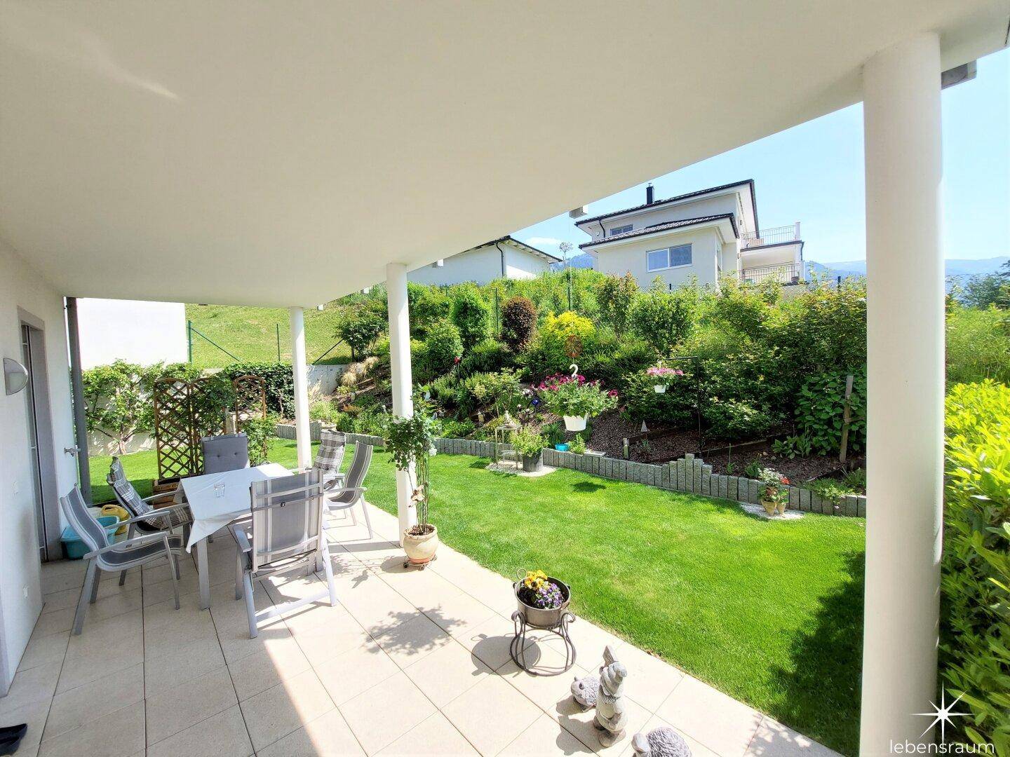 Großzügige überdachte Terrasse mit Gartenmöbeln und Blick auf den gepflegten Garten.