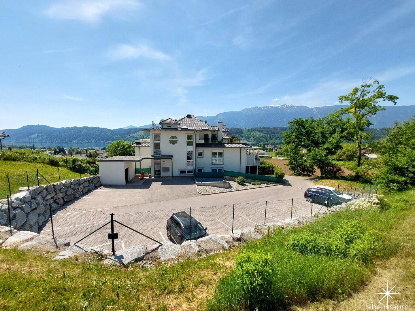Weitläufige Außenansicht des Anwesens mit Parkplätzen und Bergblick in der Ferne.