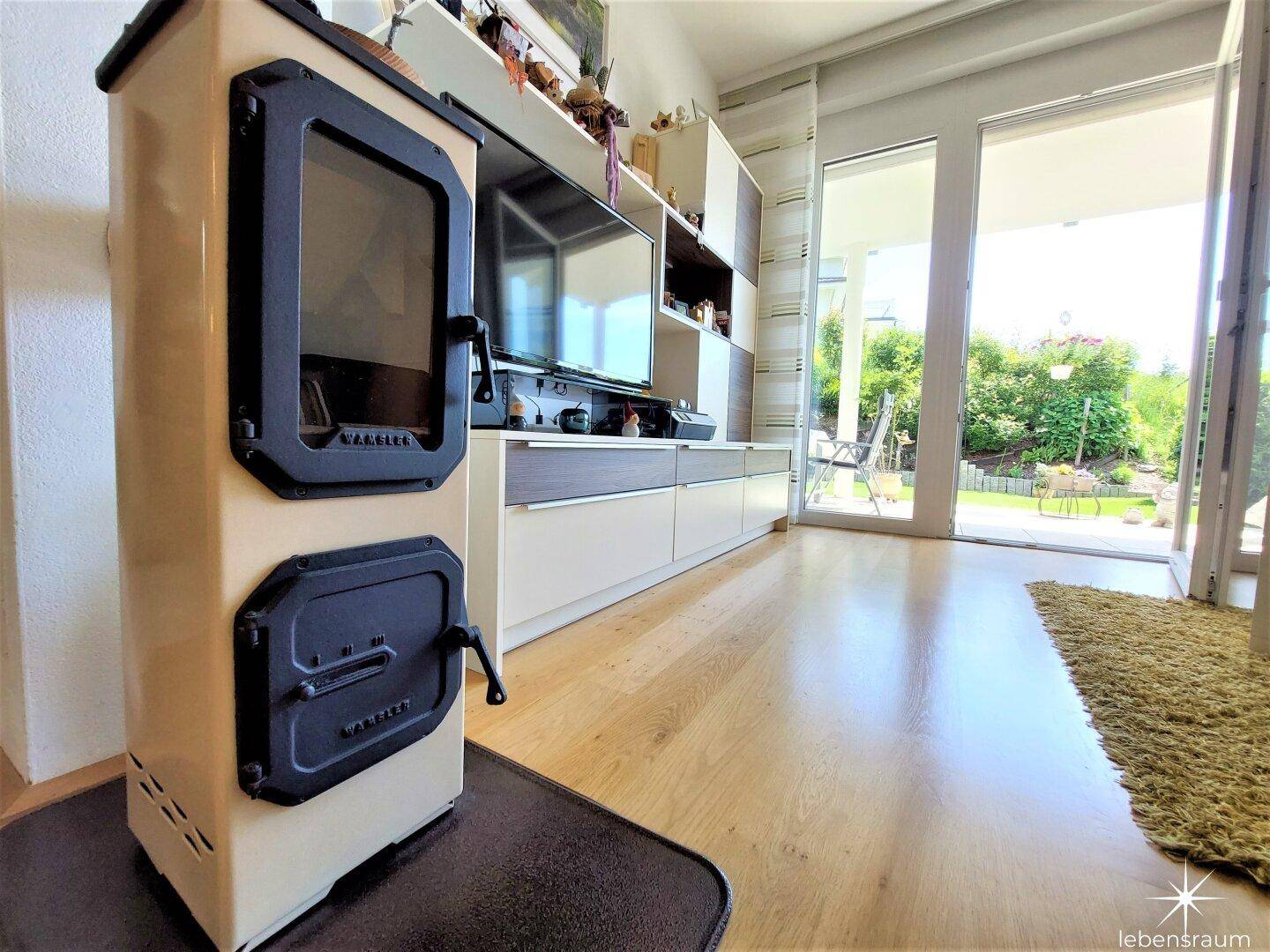 Gemütliches Wohnzimmer mit Holzboden und einem modernen Holzofen für kalte Tage.