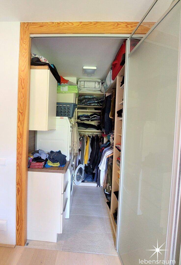 Praktischer begehbarer Kleiderschrank mit viel Stauraum und integrierter Waschmaschine.