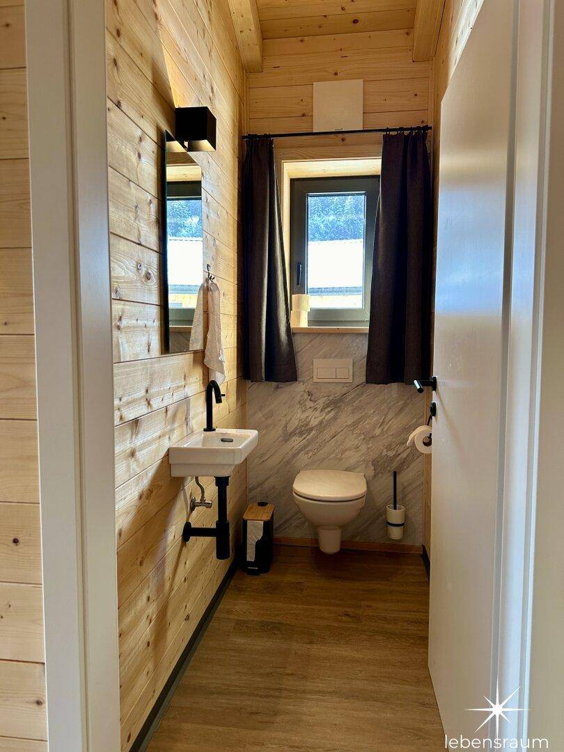 Kleines Gäste-WC mit Waschbecken, Toilette und Fenster für Tageslicht.