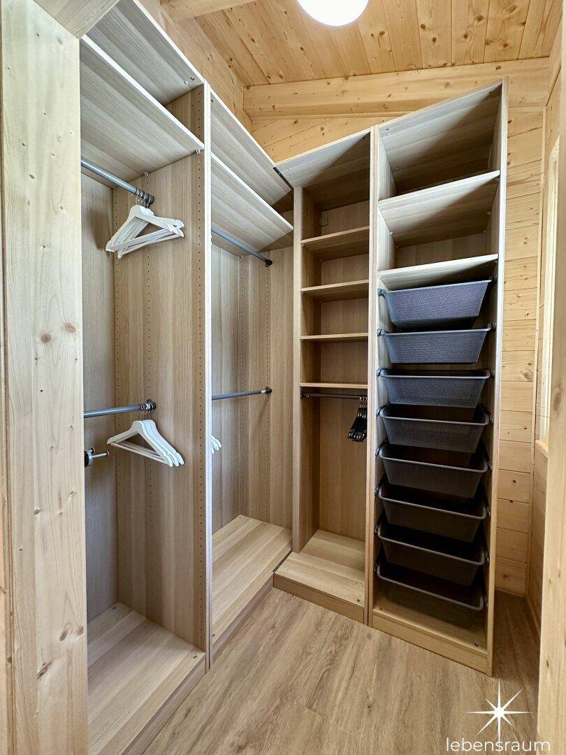 Praktischer begehbarer Kleiderschrank mit Holzregalen und viel Stauraum.