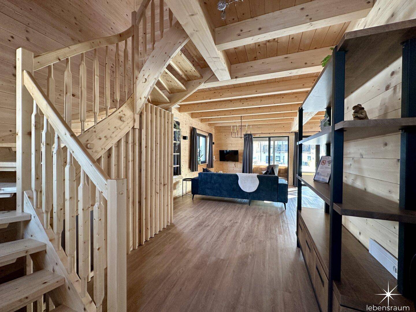 Heller Eingangsbereich mit Holztreppe und Blick in den offenen Wohnbereich.