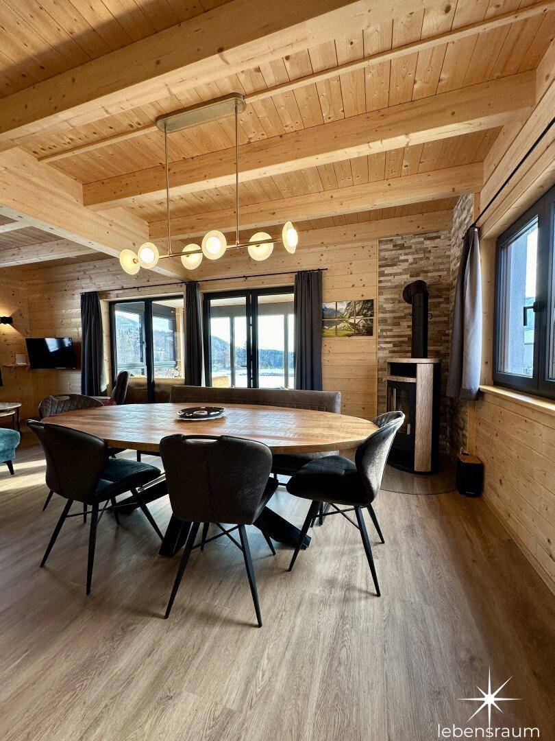 Geräumiger Essbereich mit großem Holztisch, modernen Stühlen und Kaminofen.