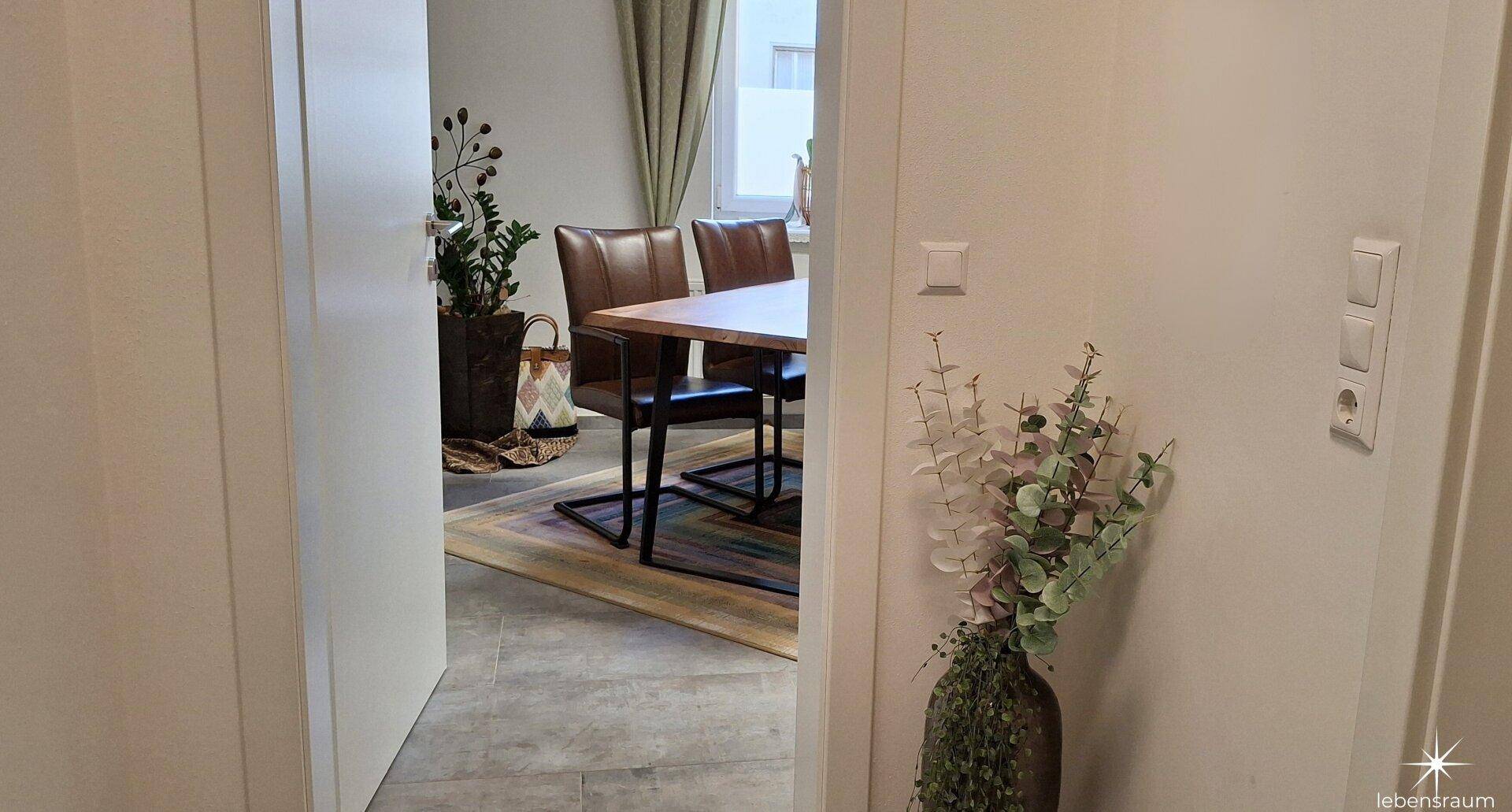 Heller Flur mit Blick in den Essbereich, ausgestattet mit modernen Bodenfliesen und einer dekorativen Pflanze.