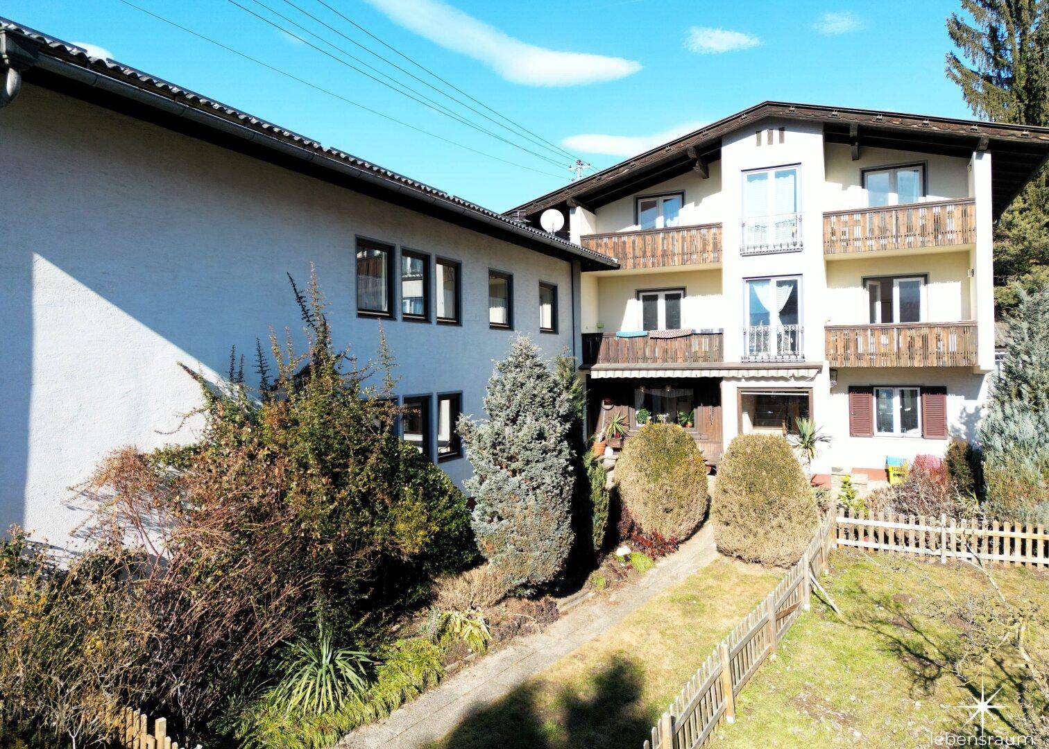 Ansicht des Mehrfamilienhauses mit Balkonen und gepflegtem Vorgartenbereich.
