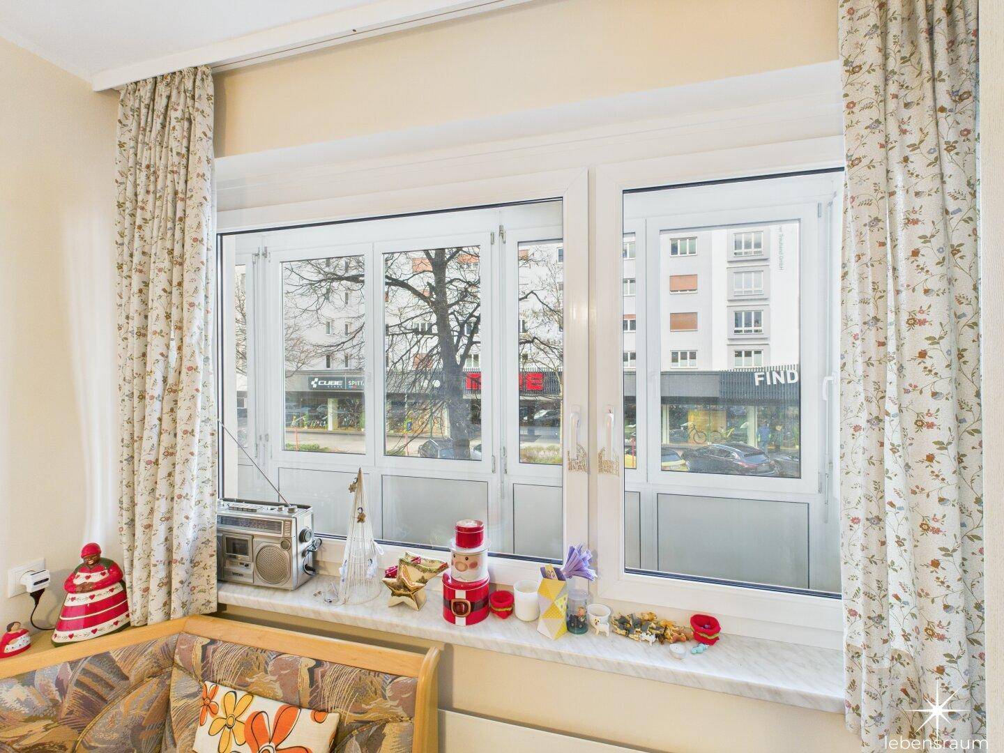 Fensterbereich der Küche mit Blick auf die Straße und dekorativen Vorhängen.