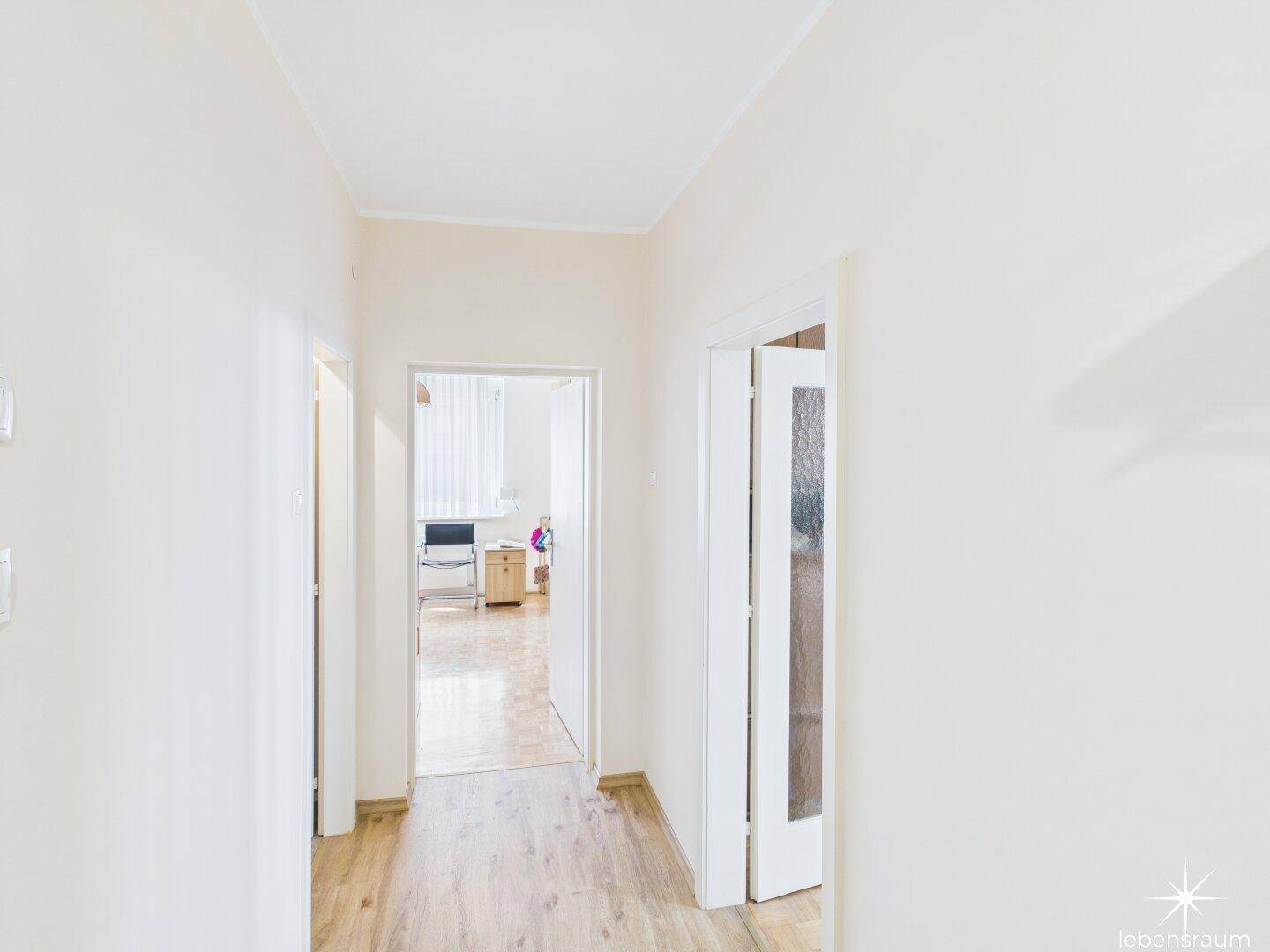 Heller Flur mit Türen zu den angrenzenden Räumen und durchgehendem Laminatboden.