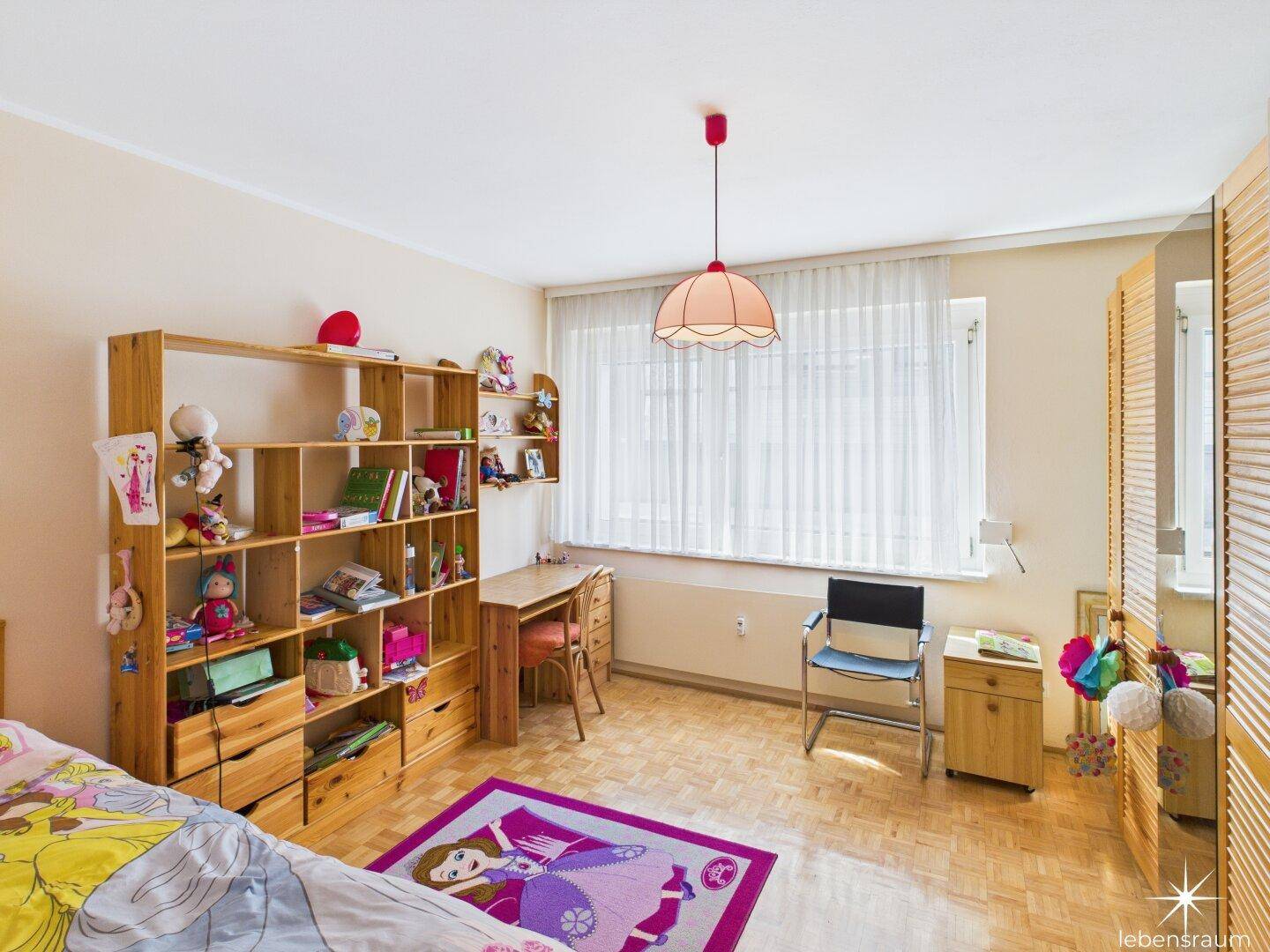 Kinderzimmer mit Holzbett, Schreibtisch, Bücherregal und Parkettboden.