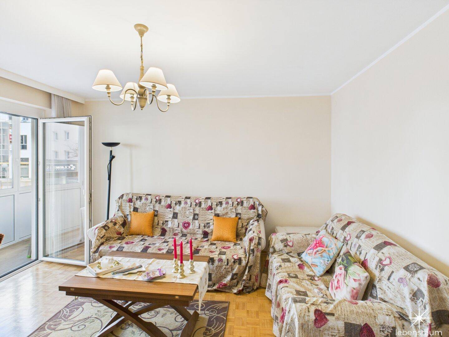 Helles Wohnzimmer mit bequemen Sofas und direktem Zugang zum verglasten Außenbereich.