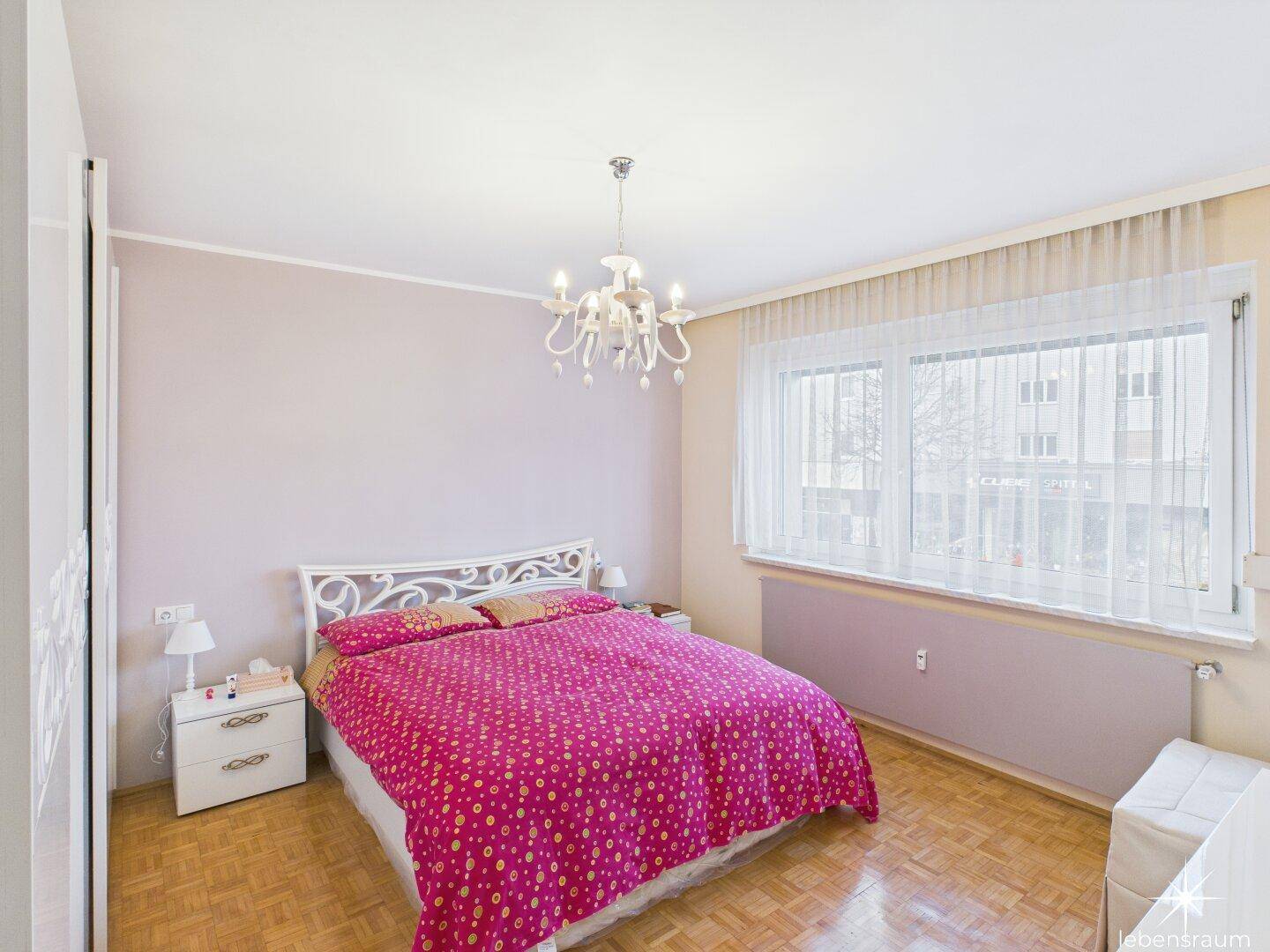 Schlafzimmer mit Doppelbett, Nachttischen und einem großen Fenster für viel Tageslicht.